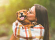 Young woman hugging and kissing dog. Dog and owner together outdoors. Love and friendship between dog and owner.